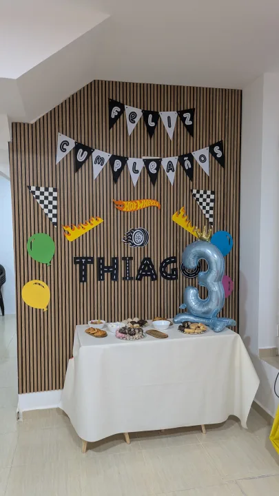 Rincón de cumpleaños con banderines, decoración de coches y una mesa de dulces.