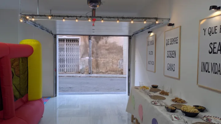 Entrada abierta del local con una mesa de celebración y un castillo hinchable.