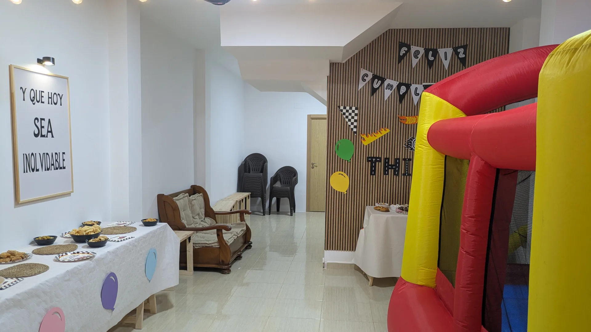 Interior del local con mesas preparadas, decoración de cumpleaños y un castillo hinchable.
